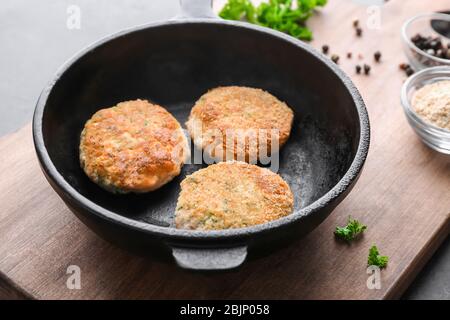 Bratpfanne mit Lachspasteten auf Holzbrett Stockfoto