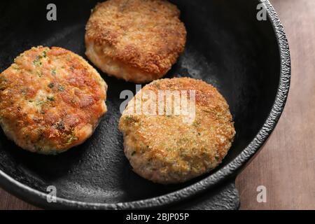 Bratpfanne mit Lachspasteten auf Holzbrett, Nahaufnahme Stockfoto