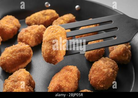 Spatel mit Lachs-Krokette über Bratpfanne, Nahaufnahme Stockfoto