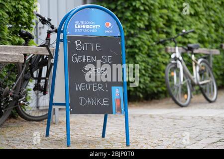 Dresden, Deutschland. April 2020. Ein Schild mit der Aufschrift "Bitte sofort weiterziehen" befindet sich auf einem Wochenmarkt in einer Eisdiele. In Sachsen wurden die Lebensbeschränkungen im Kampf gegen die Corona-Pandemie vorsichtig gelockert, doch im Einzelhandel sind Masken Pflicht. Quelle: Sebastian Kahnert/dpa-Zentralbild/dpa/Alamy Live News Stockfoto