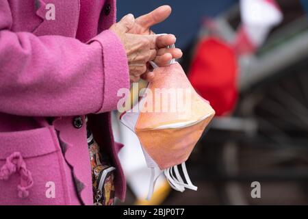 Dresden, Deutschland. April 2020. Eine Frau verkauft selbstgenähte Mundschutz auf einem Wochenmarkt für jeweils 6.50 Euro. In Sachsen wurden die Lebensbeschränkungen im Kampf gegen die Corona-Pandemie vorsichtig gelockert, im Einzelhandel sind aber Masken Pflicht. Quelle: Sebastian Kahnert/dpa-Zentralbild/dpa/Alamy Live News Stockfoto