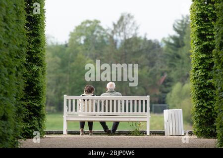 Dresden, Deutschland. April 2020. Passanten sitzen auf einer Bank im Schlosspark Pillnitz. Quelle: Sebastian Kahnert/dpa-Zentralbild/dpa/Alamy Live News Stockfoto