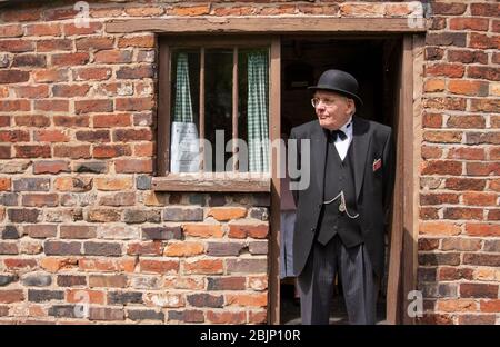 Ein älterer Mann, der in authentische Kleidung der 1940er Jahre gekleidet war, stand im Hintereingang eines roten Backsteinhauses. Birmingham, England, Großbritannien Stockfoto