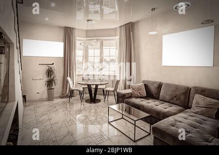 Moderne Einrichtung eines großen und gemütlichen Wohnzimmers mit Sofa und Tisch am Fenster. Mockup an der Wand. Stockfoto