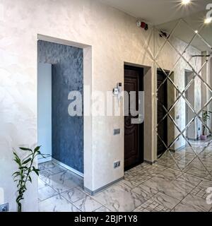 Blick auf das Foyer im Inneren. Helles Interieur einer schönen modernen Halle im Stil des Minimalismus mit weißen Wänden, einem schönen Kronleuchter, einem großen mir Stockfoto