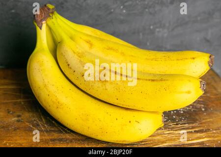Drei Bananen liegen auf alten Holzbrettern. Nahaufnahme Stockfoto