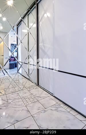 Blick auf das Foyer im Inneren. Helles Interieur einer schönen modernen Halle im Stil des Minimalismus mit weißen Wänden, einem schönen Kronleuchter, einem großen mir Stockfoto