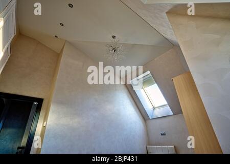 Helle mehrstufige verputzte Decke in einem modernen Dachgeschoss mit Dormer-Fenster Stockfoto
