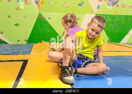 Entzückende kleine Kinder, die in der Kletterhalle Schuhe anziehen Stockfoto