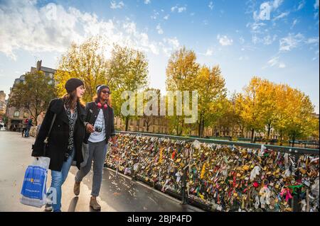 Freundinnen reisen in Paris und sehen zwei junge Freundinnen, die an einem Herbsttag in Frankreich über den Pont de l'Archeveche im Zentrum von Paris spazieren. Stockfoto