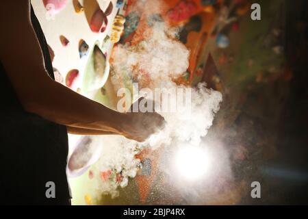 Junger Mann, der Talkpulver auf die Hände in der Kletterhalle anwendet Stockfoto