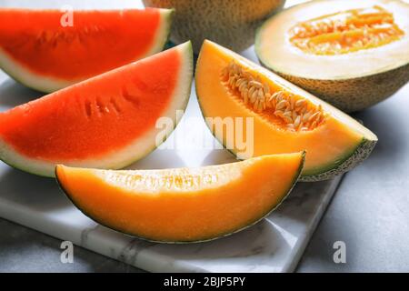 Marmorplatte mit Scheiben frischer Melone und Wassermelone auf dem Tisch, Nahaufnahme Stockfoto