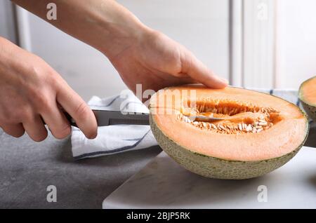 Frau schneidet Melone auf Küchentisch Stockfoto