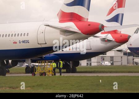 Glasgow, Großbritannien. April 2020. Im Bild: Gewitterwolken sammeln sich, als die Bodencrews von British Airways die Sammlung von 14 geerdeten Flugzeugen des Typs Airbus A319/A320 & A321 in Betrieb nehmen, die seit Beginn der Sperrung des Coronavirus (COVID-19) auf der zweiten Start- und Landebahn des Flughafens Glasgow geparkt wurden. Die globale Luftfahrtindustrie ist seitdem in eine Kernschmelze geritten, einige Fluggesellschaften gehen in die Pleite und andere wie BA bitten um staatliche finanzielle Unterstützung. Bis heute hat BA angekündigt, dass es fast 12,000 Mitarbeiter zu nehmen. Quelle: Colin Fisher/Alamy Live News Stockfoto