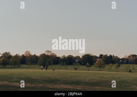 London, Großbritannien - 22. März 2020: Fernansicht von Menschen, die im Broomfield Park, einem öffentlichen Park in Palmers Green im Londoner Stadtteil Enfield, Großbritannien, spazieren gehen Stockfoto