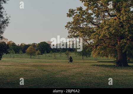 London, Großbritannien - 22. März 2020: Fernansicht von Menschen, die im Broomfield Park, einem öffentlichen Park in Palmers Green im Londoner Stadtteil Enfield, Großbritannien, spazieren gehen Stockfoto