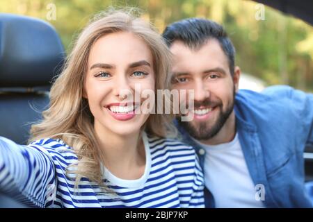 Glückliches junges Paar unter selfie im Auto. Stockfoto