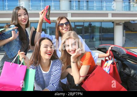 Schöne junge Frauen mit Einkaufstaschen im Cabrio im Freien Stockfoto