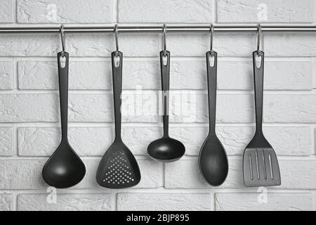 Küchenutensilien hängen an einer Wand aus Ziegelstein Stockfoto