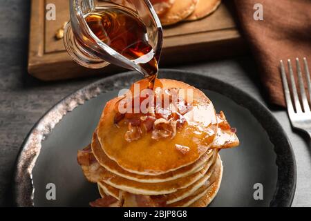 Honig auf Pfannkuchen gießen und Speck auf Teller legen Stockfoto