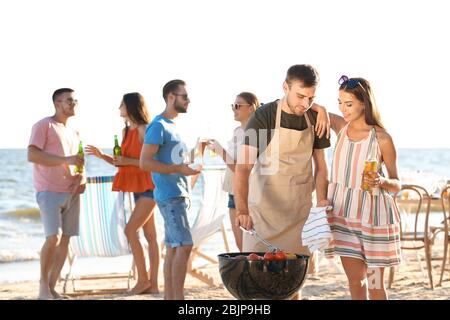 Junge Leute mit Grillparty am Strand Stockfoto