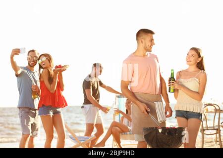 Junge Leute mit Grillparty am Strand Stockfoto