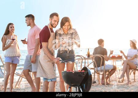 Junge Leute mit Grillparty am Strand Stockfoto