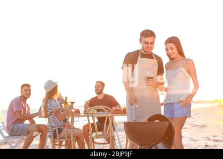 Junge Leute mit Grillparty am Strand Stockfoto