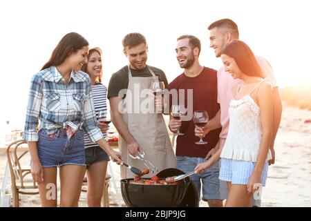 Junge Leute mit Grillparty am Strand Stockfoto