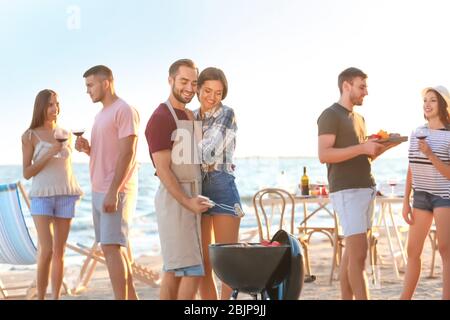 Junge Leute mit Grillparty am Strand Stockfoto