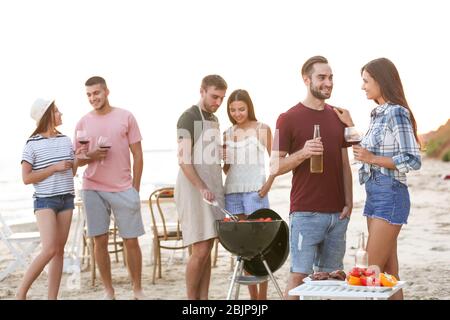 Junge Leute mit Grillparty am Strand Stockfoto