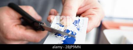 Männliche Hand schneiden Bankkarte mit Schere Stockfoto
