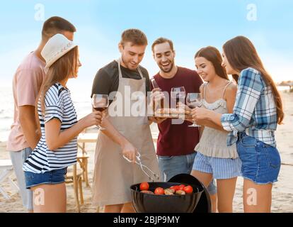 Junge Leute mit Grillparty am Strand Stockfoto