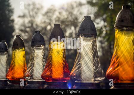 Auf einem Grabstein auf dem Rakowicki Friedhof in Krakau, Polen 2019, steht eine Reihe von Kerzen. Stockfoto