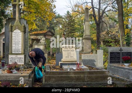 Ein Mann reinigt einen Grabstein auf dem Rakowicki Friedhof in Krakau, Polen 2019. Stockfoto