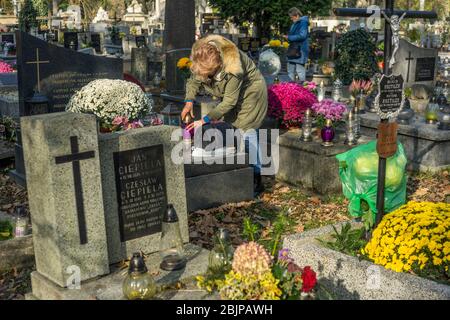 Eine Frau zündet eine Kerze auf dem Rakowicki Friedhof in Krakau, Polen 2019 an. Stockfoto