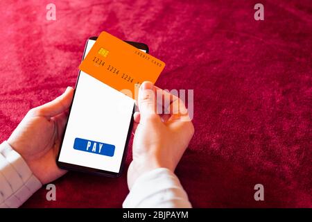 Menschliche Hand hält Smartphone mit Online-Shopping-App und Kreditkarte. Stockfoto
