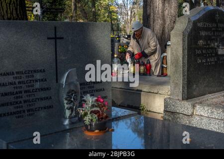 Eine Frau zündet eine Kerze auf dem Rakowicki Friedhof in Krakau, Polen 2019 an. Stockfoto