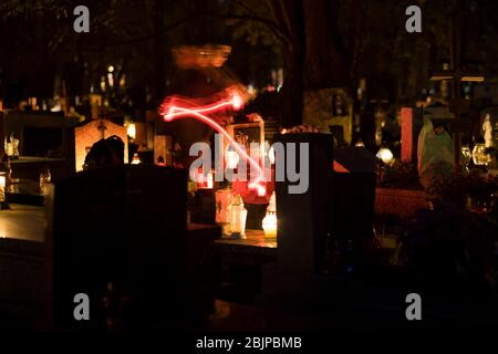 Ein Mann zündet am Abend auf dem Rakowicki Friedhof in Krakau, Polen 2019, eine Kerze an. Stockfoto