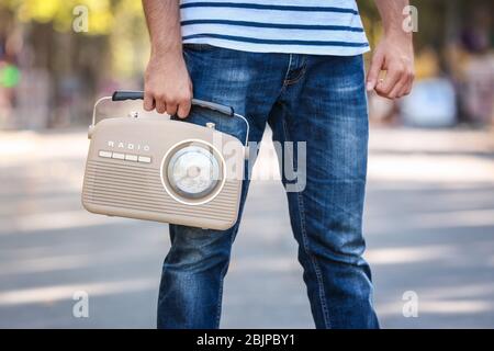 Junger Mann mit Retro-Radio im Freien Stockfoto