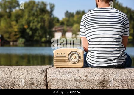 Junger Mann mit Retro-Radio im Freien Stockfoto