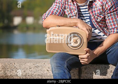 Junger Mann mit Retro-Radio im Freien Stockfoto