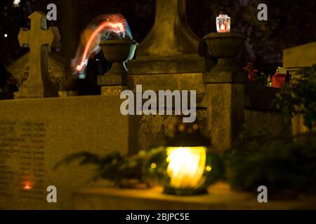 Ein Mann zündet am Abend auf dem Rakowicki Friedhof in Krakau, Polen 2019, eine Kerze an. Stockfoto