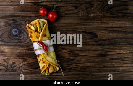 Döner wickeln Kebab. Shawarma mit Fleisch, Zwiebeln, Salat liegt auf einem dunklen alten Holztisch. Von oben mit viel Platz Stockfoto