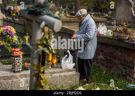 Eine Frau zündet eine Kerze auf dem Rakowicki Friedhof in Krakau, Polen 2019 an. Stockfoto