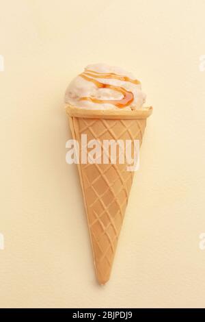 Waffelkegel mit Karamell-Eis auf hellem Hintergrund Stockfoto
