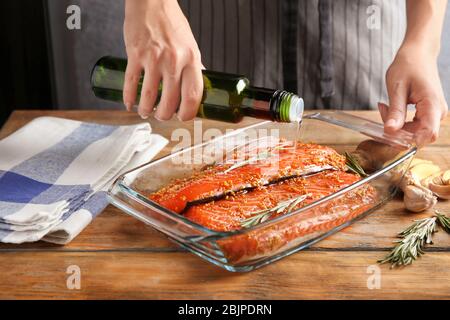 Frau bereitet Lachsfilet mit Marinade in Backform Stockfoto