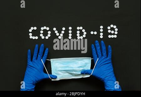 Medizinische Maske in Arzthand mit Schutzhandschuhen. Blauer Hintergrund. Coronavirus-Konzept. Pandemie in der Welt. Stockfoto