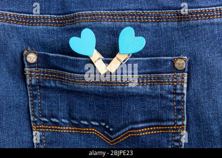 Kleine Holzherz Wäscheklammern an einer Denim-Tasche befestigt. Kleine Wäscheklammern mit blauen Herzen auf der Tasche der blauen Jeans Stockfoto