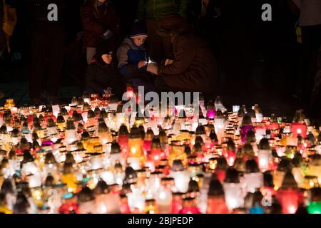 Ein Junge und seine Mutter zünden eine Kerze vor dem Denkmal für die polnischen Opfer des Kommunismus auf dem Rakowicki Friedhof in Krakau, Polen 2019 an. Stockfoto